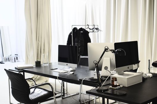 Interior of contemporary empty office with modern computers and large windows with curtains