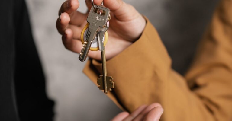 Two adults exchanging house keys, symbolic of property transfer or rental agreement.
